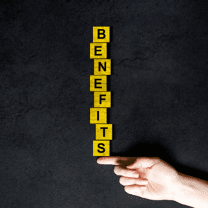 Yellow blocks with black letters stacked to read benefits and balanced on on finger.